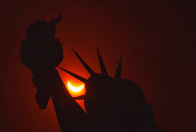 The eclipsed sun passing behind the Statue of Liberty in New York City